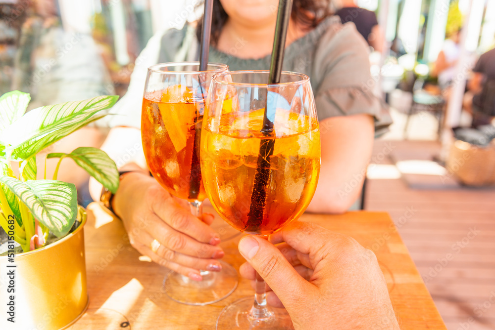 Woman and man making a celebratory toast with aperol spritz orange alcoholic cocktails at outdoors cocktail bar.Close up. Woman and man making a celebratory toast with aperol spritz orange alcoholic cocktails at outdoors cocktail bar.Close up.