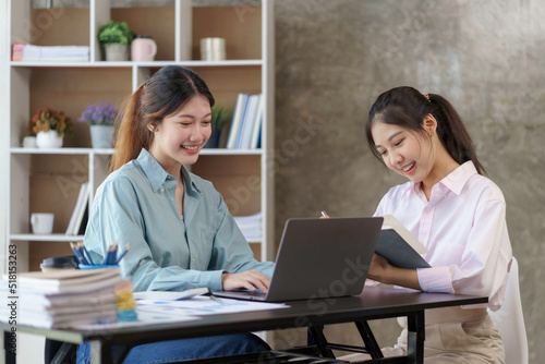 Two young Asian businesswomen discuss with new startup project Idea presentation, analyze planning and financial statistics and investment market on laptop computer at office.