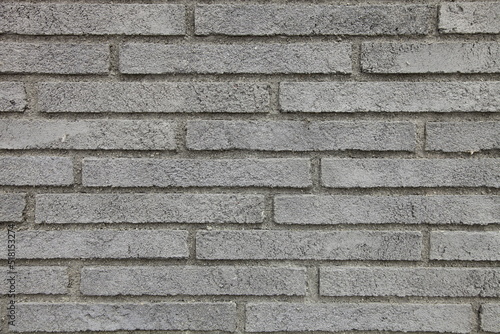 Textured background of the wall is made of gray narrow and long bricks.