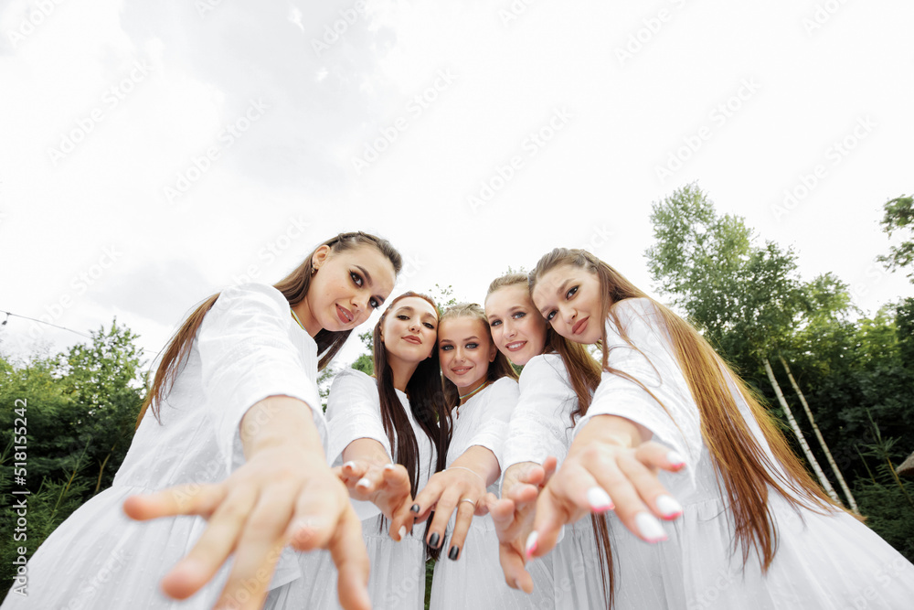 Stylish Ukrainian women in white dresses pose in the yard. Wide-angle view.