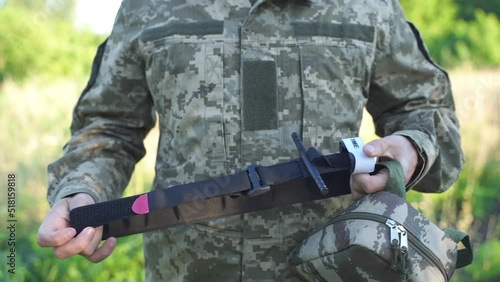 a military man in uniform holds a tourniquet in his hands, preparing it for use. combat medicine, training of combat medics. stopping massive bleeding. medics on the battlefield. first aid