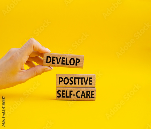 Develop positive self-care symbol. Concept words Develop positive self-care on wooden blocks. Beautiful yellow background. Businessman hand. Business and Develop positive self-care concept. Copy space