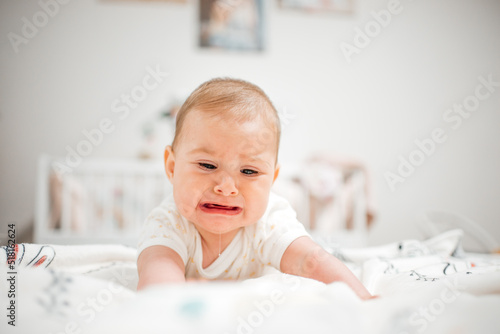 Screaming child lies on his stomach on the bed