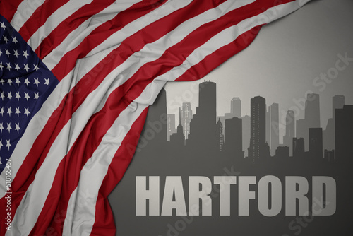 abstract silhouette of the city with text hartford near waving colorful national flag of united states of america on a gray background. photo