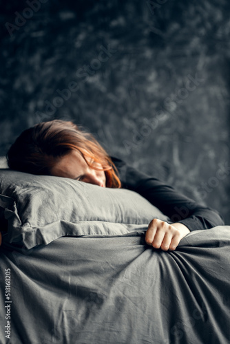 Sad woman lying on pillow, clenching sheet. Mental health, depression.