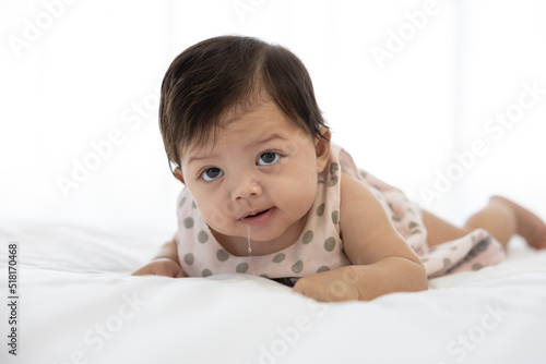 cute baby crawling on bed and drooling from mouth photo