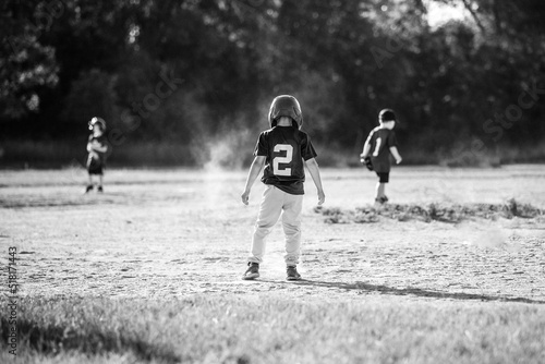 Black and white of a boy standing on a base playing baseball