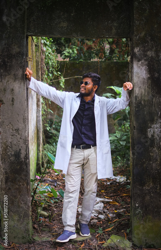 South asian medical student wearing white apron and sunglass, Bangladeshi young confident male doctor in outdoor environment, your aged man as a fashion model