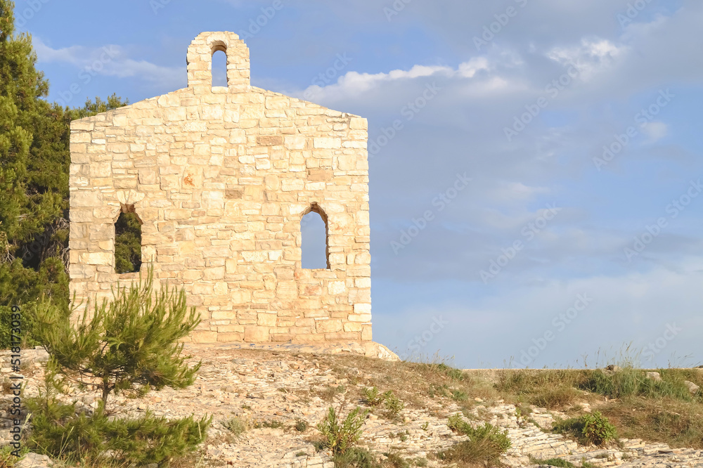 Restored religious church wall in Verudela on a rocky seashore