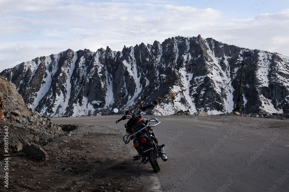Motorcycle standing on mountain road in Himalayan mountains among high stone snowy cliffs