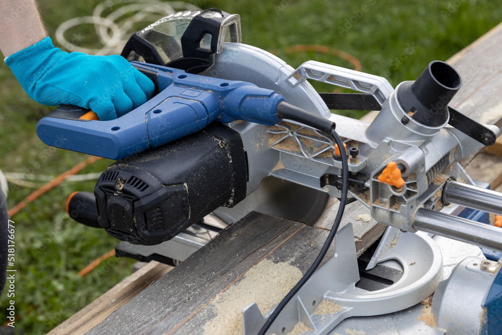 Miter circular saw photographed in the process of work. Tool for carpentry. A man works with a tool. The worker saws the boards. Sawmill. Miter saw for cutting wood at work. Miter circular saw photographed in the process of work. Tool for carpentry. A man works with a tool. The worker saws the boards. Sawmill. Miter saw for cutting wood at work.