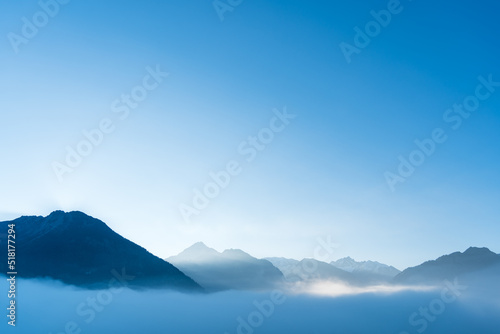 Blue moutains silhouette with fog in the valley. Beautiful fresh and bright morning in the alps.