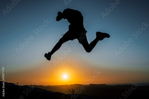 Silhouette of a boy jumping with the sunset behind him. Summer feelings