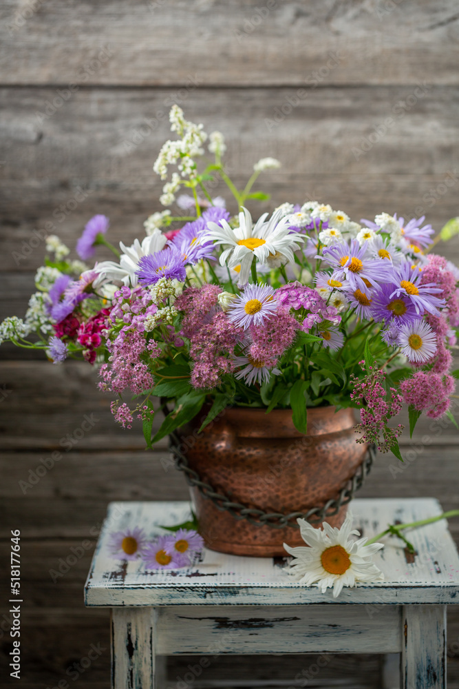 Summer bouquet of garden flowers with chamomile and Aster alpinus in a copper pot