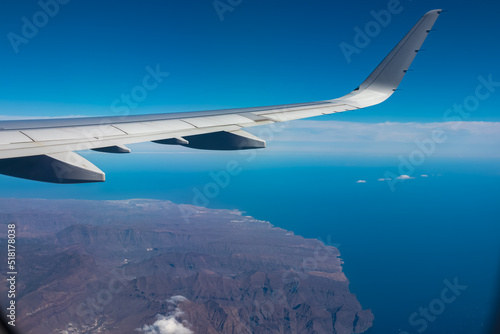 Aerial window view from an airplane on Gran Canaria, Canary Islands, Spain, Europe, EU. Wing and turbines of the aircraft can be seen. Flying high above the ground. Freedom. Flying into vacation