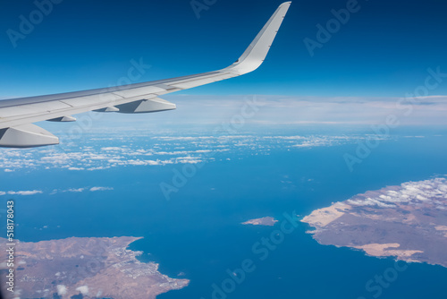 Aerial window view from an airplane on Fuerteventura and Lanzarote, Canary Islands, Spain, Europe, EU. Wing and turbines of the aircraft can be seen. Flying high above the ground. Freedom. Flying