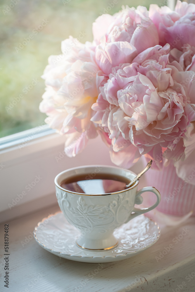 Cup of tea with pink peonies in a vase Cup of tea with pink peonies in a vase