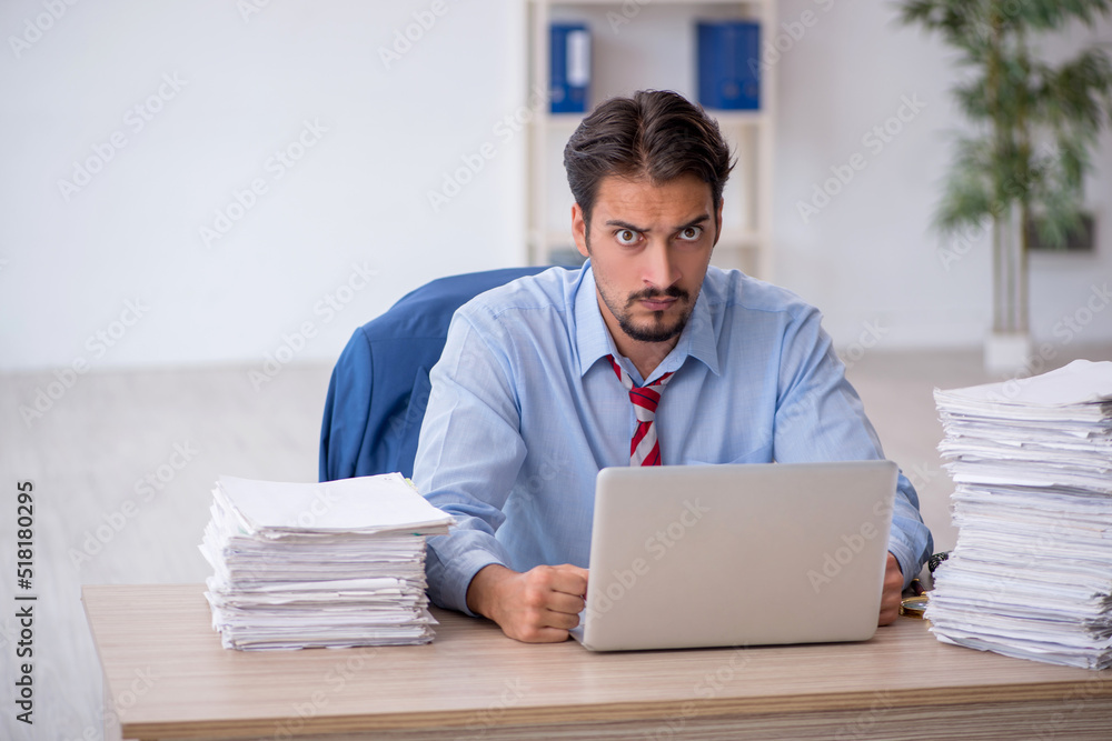 Young male employee and too much work in the office Young male employee and too much work in the office