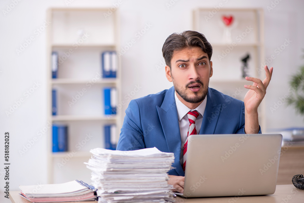 Young male employee and too much work in the office Young male employee and too much work in the office