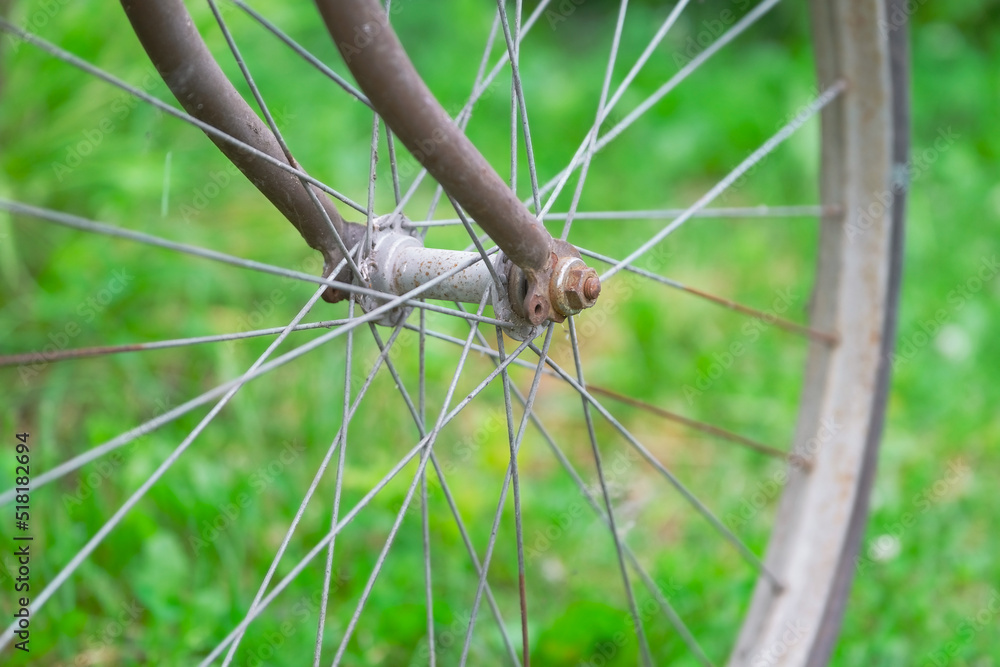 wheel of an old bicycle close-up against green grass, dirty and rusty hub and spokes of a vintage bike wheel of an old bicycle close-up against green grass, dirty and rusty hub and spokes of a vintage bike