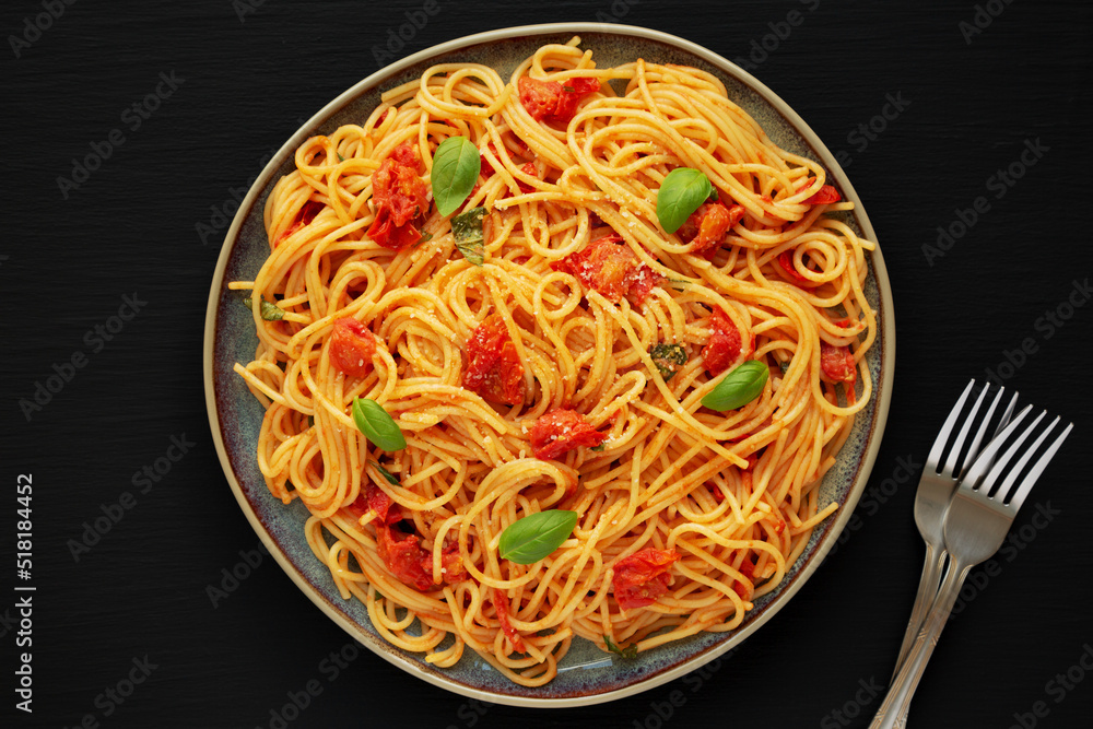 Homemade Spaghetti Pasta with Fresh Tomato Sauce on a Plate on a black surface, top view. Flat lay, overhead, from above. Copy space. Homemade Spaghetti Pasta with Fresh Tomato Sauce on a Plate on a black surface, top view. Flat lay, overhead, from above. Copy space.