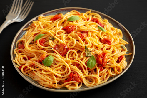 Homemade Spaghetti Pasta with Fresh Tomato Sauce on a Plate on a black surface, side view.