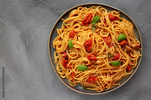Homemade Spaghetti Pasta with Fresh Tomato Sauce on a Plate on a gray surface, top view. Flat lay, overhead, from above. Copy space.