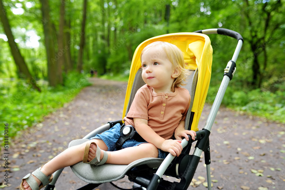 Sweet toddler boy sitting in a stroller outdoors. Little child in pram. Infant kid in pushchair. Summer walks with kids. Sweet toddler boy sitting in a stroller outdoors. Little child in pram. Infant kid in pushchair. Summer walks with kids.