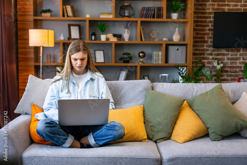 Upset woman using a laptop in her living room. Working from home in quarantine lockdown. Social distancing Self Isolation photo