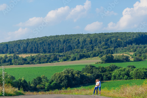 girl in casual wear walks in the field with young guy also in ca