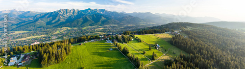 Aerial view of Zakopane town underneath Tatra Mountains taken from the Gubalowka mountain range. High mountains and green hills in summer or spring.