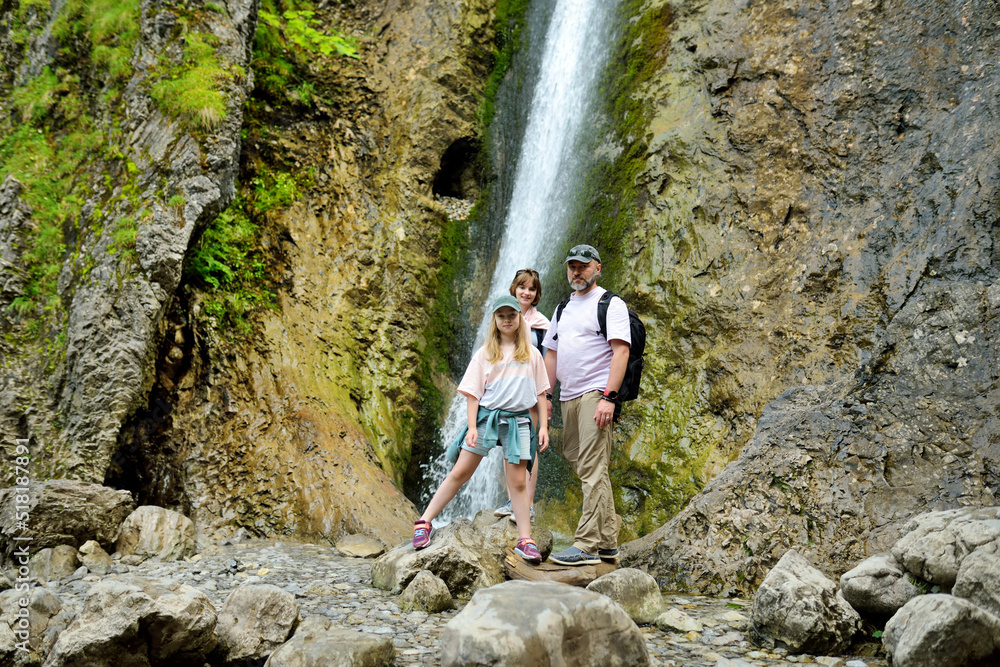 Father and his two daughters admiring Siklawica Waterfall in Strazyska Valley in Tatra Mountains, Poland.