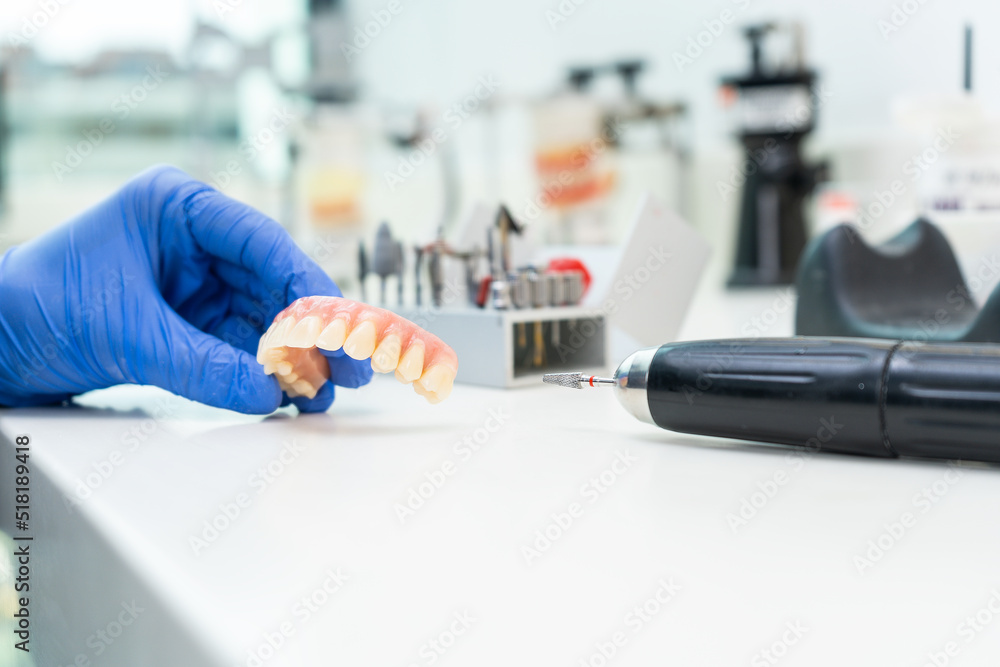 Dental technician hand holding denture in dental laboratory