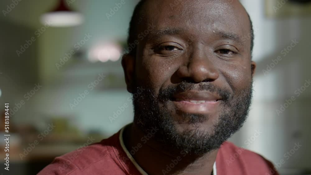 Portrait of cheerful African American man looking at camera and smiling in evening at home Portrait of cheerful African American man looking at camera and smiling in evening at home