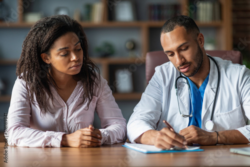 Middle eastern doctor taking anamnesis of african american lady patient