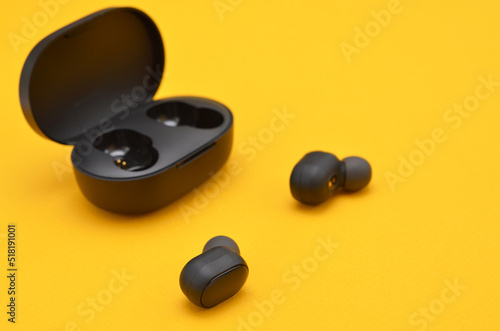 a charger and wireless headphones on yellow background close up