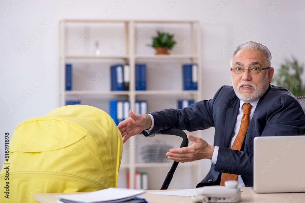 Old male employee looking after new born at workplace Old male employee looking after new born at workplace