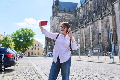 Woman tourist taking a selfie in front of an ancient European cathedral