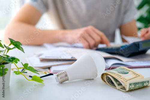A man counts a bill on a calculator and a check for electricity on the table. Payment of utility services. Saving energy and money concept.