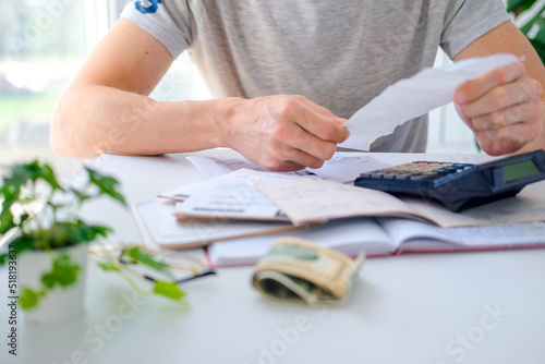 A man looks at a sales receipt and counts on a calculator. Payment of utility services. The concept of saving energy and money. Shopping in the store. photo