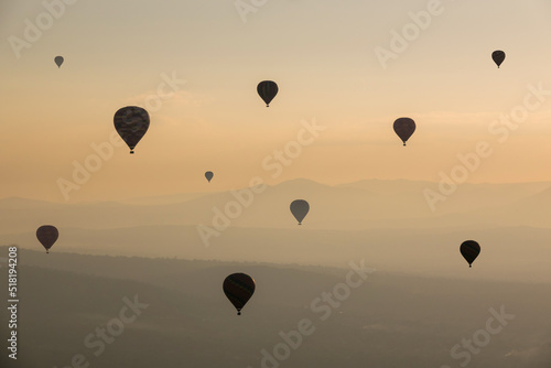 Group of Hot Air Balloons Flying Over Ancient Pyramid of Teotihuacan, Mexico at sunrise -sunset, over the mist