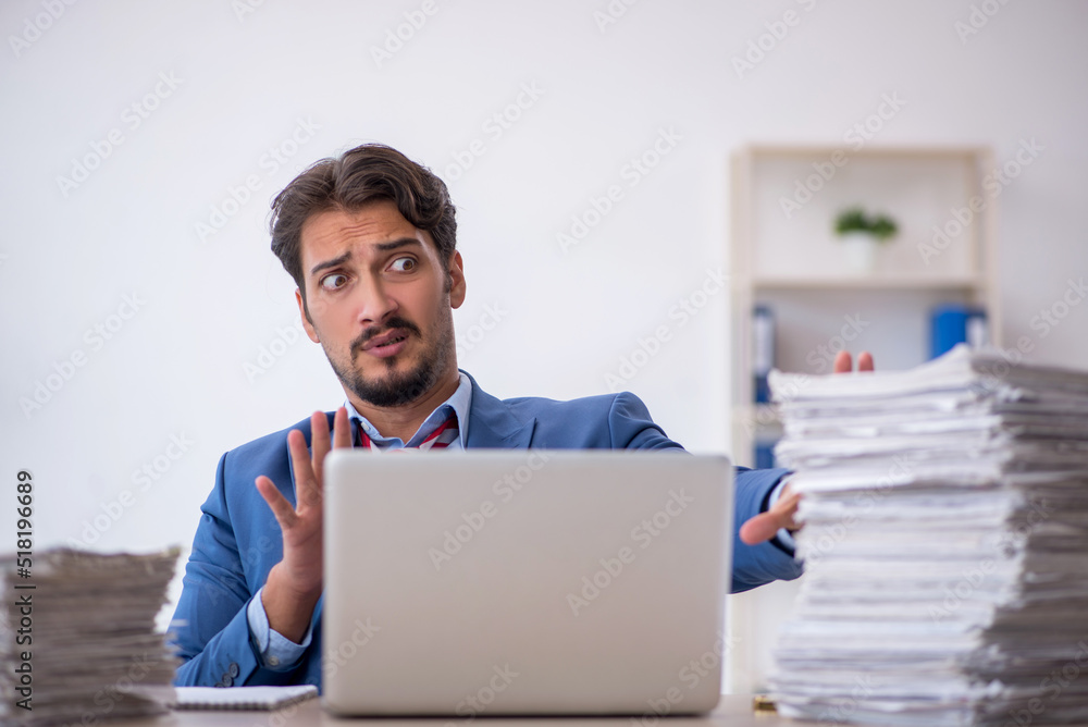 Young male employee and too much work in the office Young male employee and too much work in the office