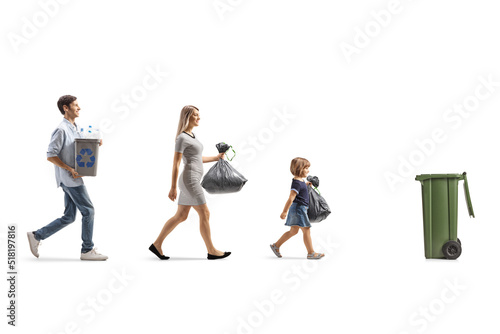 Mother, father and child walking towards trush bin to recycle photo