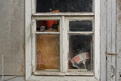 one white dirty wooden window on the gray wall of a rural house on the street