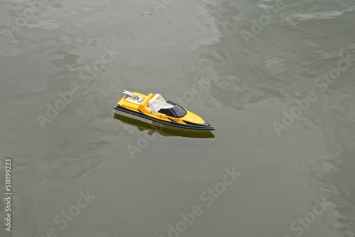 one toy colored plastic electric radio-controlled boat floats on the gray water of the lake photo