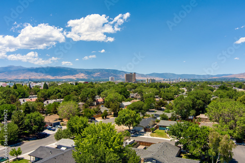 Aerial view of the Reno-Sparks Nevada downtown skyline district during summer with mature green trees and a bright blue sky with a few clouds.