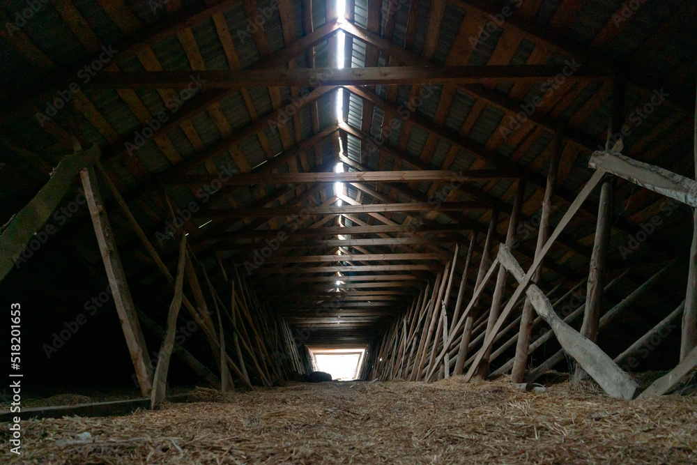 Abandoned ruined barn cowshed inside view. The old abandoned barn with the remains of feeders. barn from inside with low light Abandoned ruined barn cowshed inside view. The old abandoned barn with the remains of feeders. barn from inside with low light