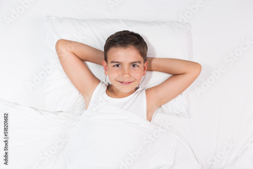 Boy in white bed, lifestyle concept. Minimal style. Top view.