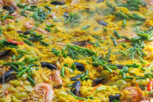 Spanish paella dish freshly being cooked with seafood and rice at a street food festival. Paella background
