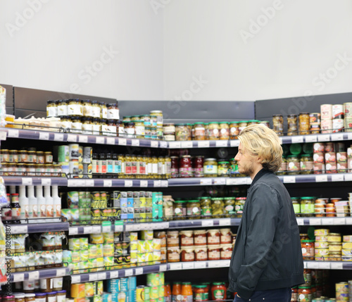 Young man shopping in supermarket, reading product information